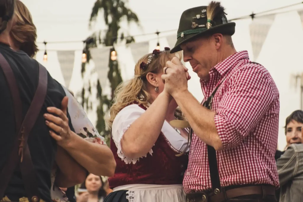Couple in traditional Bavarian attire dancing at Oktoberfest. - Lederhosen For Sale
