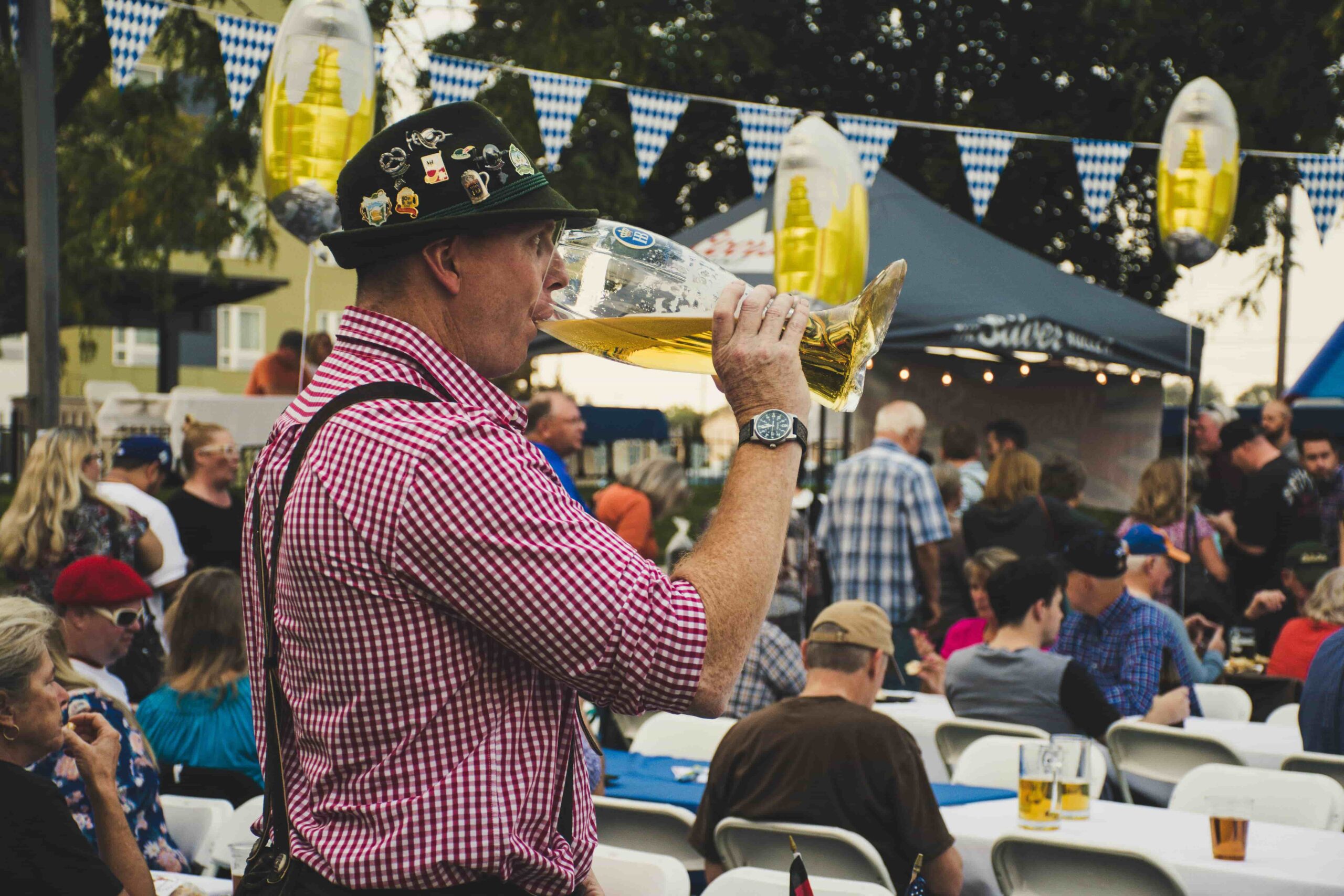 Man drinking from a boot-shaped beer glass. - Lederhosen For Sale