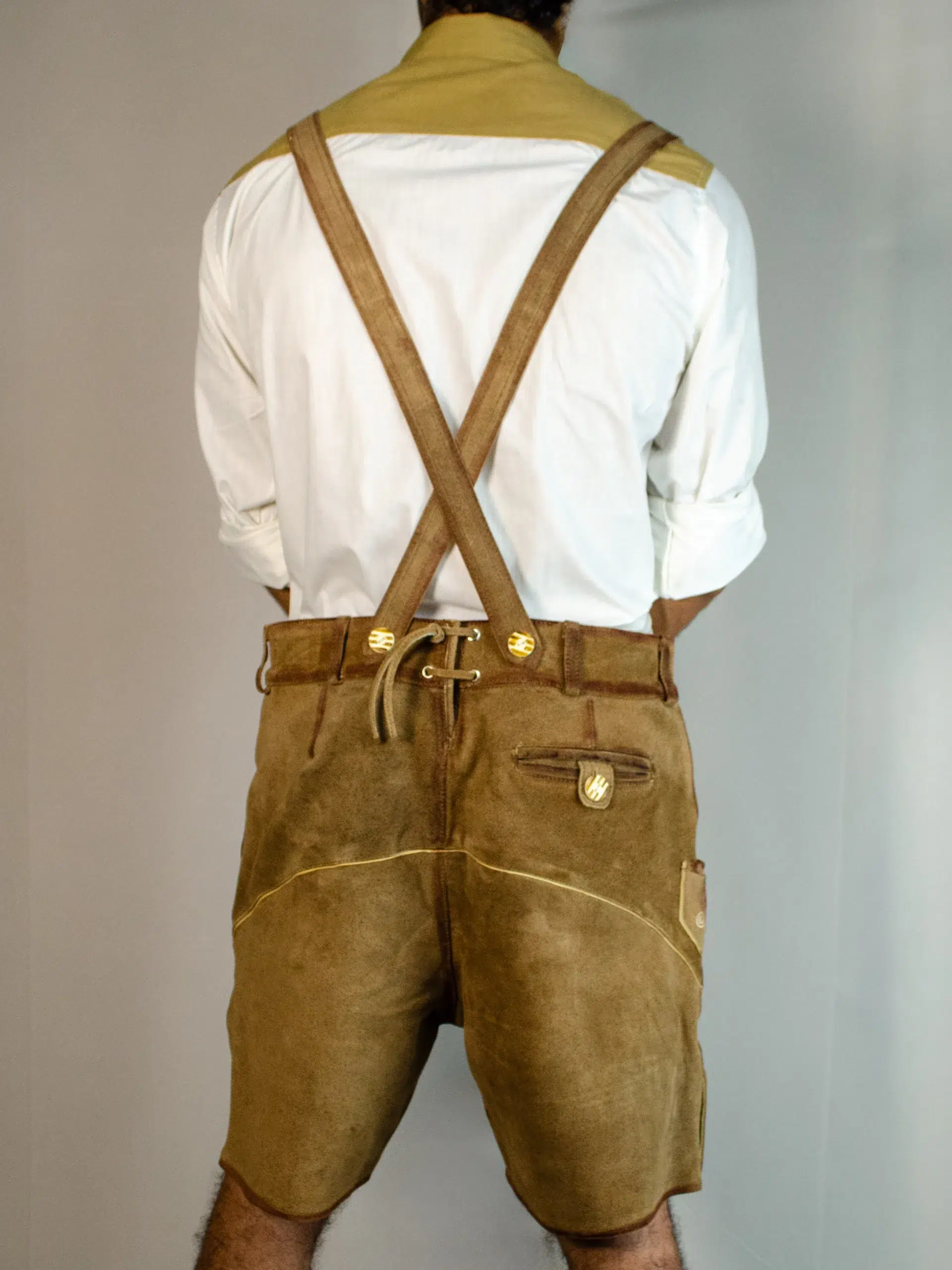 Rear view of man in tan Lederhosen with suspenders and white shirt. - Lederhosen For Sale