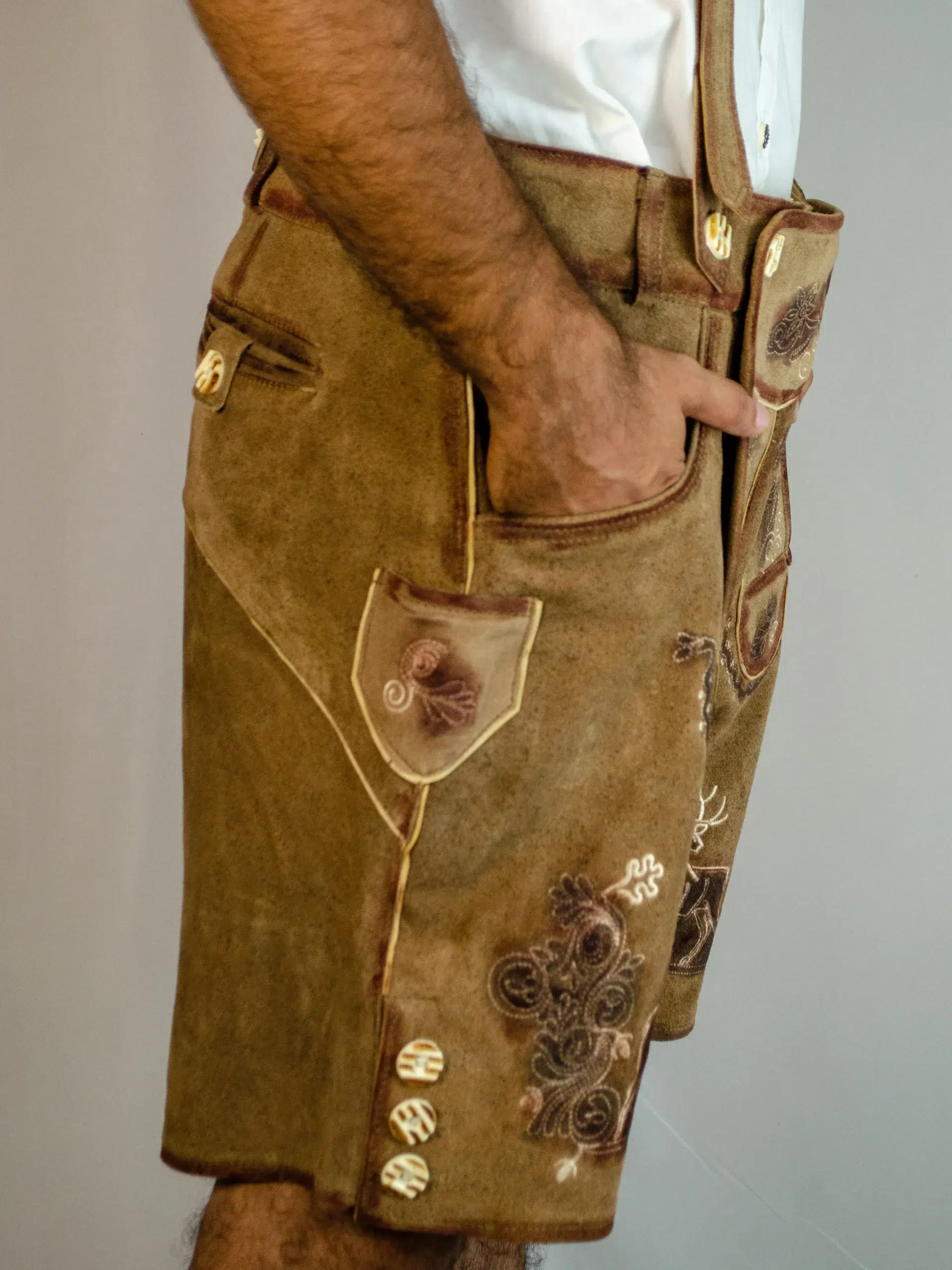 Side view close-up of tan embroidered Lederhosen with pocket details and deer motifs. - Lederhosen For Sale