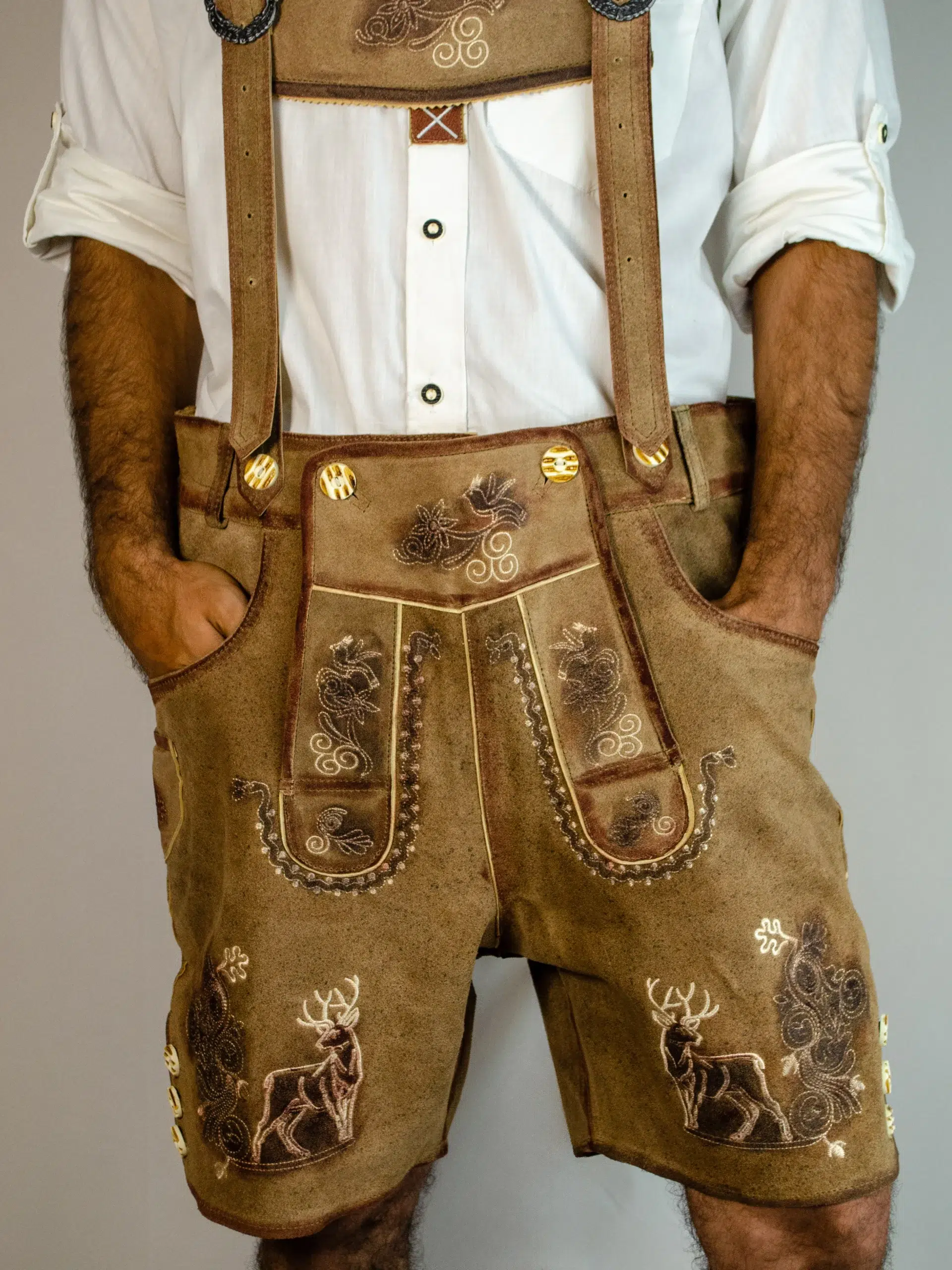 Front view close-up of tan embroidered Lederhosen with deer motifs and suspenders. - Lederhosen For Sale